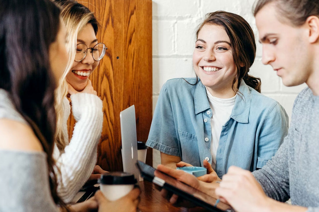 Lächelnde Personen im Beratungsgespräch mit Laptop beim AVGS-Coaching