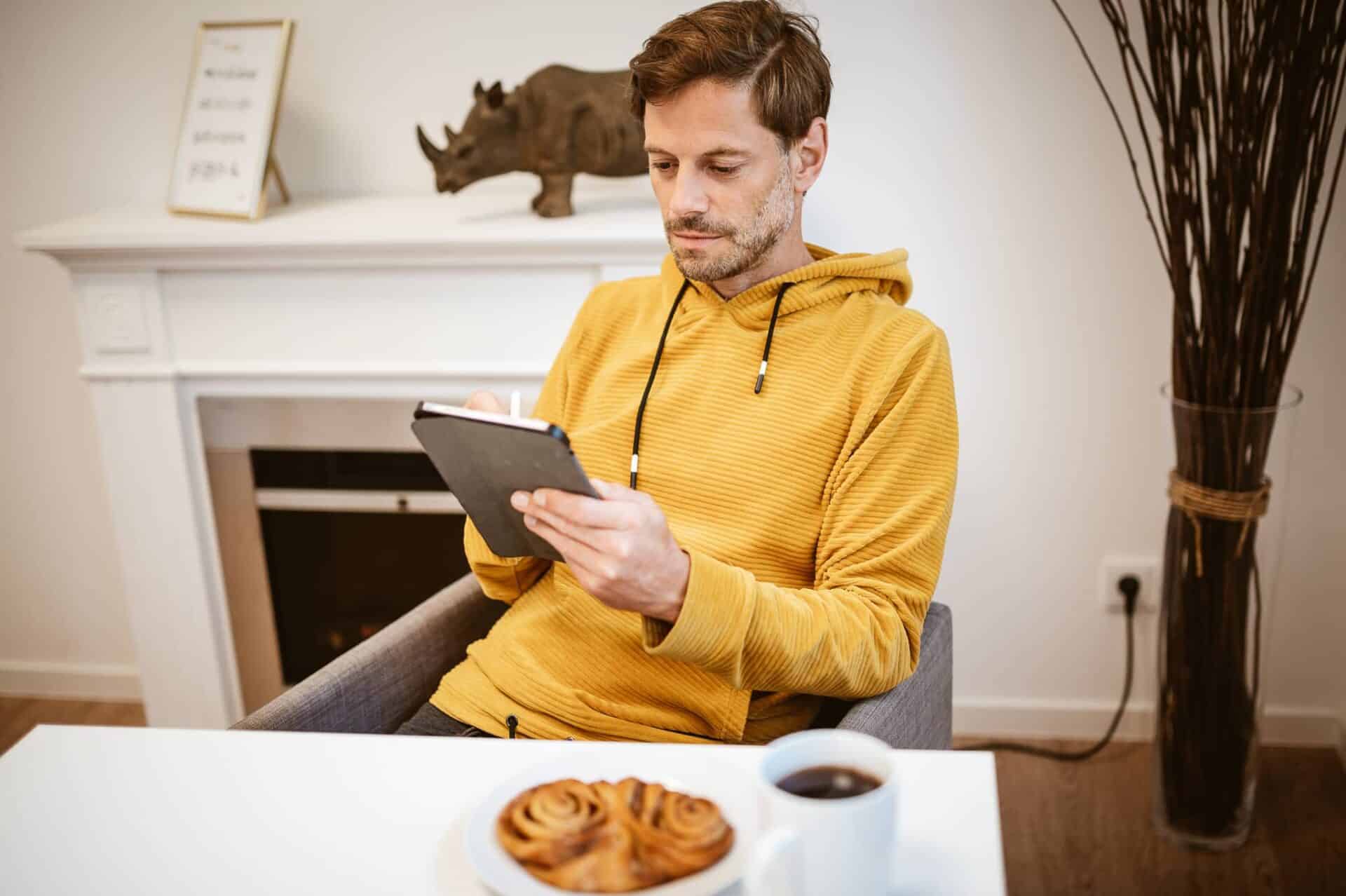 Ein junger Mann sitzt mit einem iPad an einem Tisch